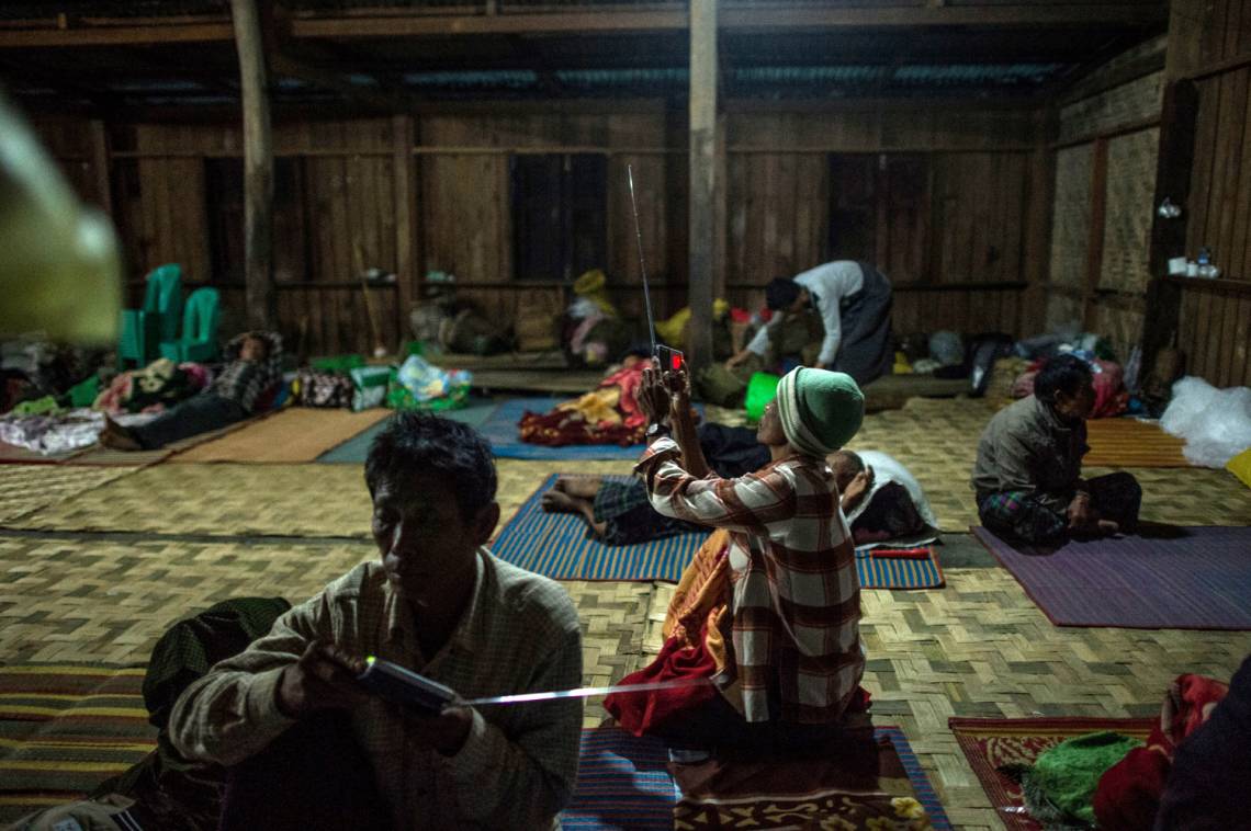 Zwei Binnenflüchtlinge hören in einer Notunterkunft in Danai im Norden Myanmars Radio. 