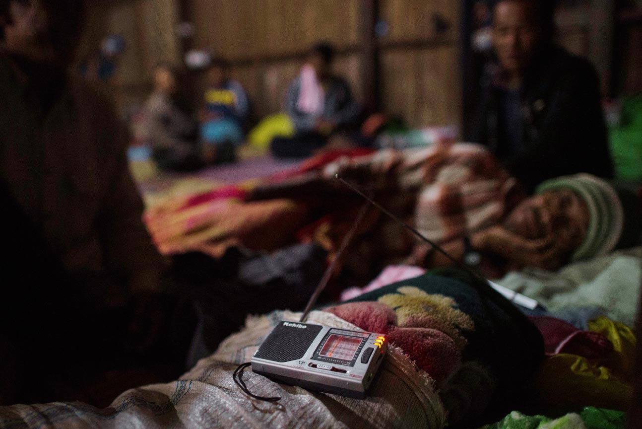 Une personne déplacée écoute la radio dans un abri temporaire à Danai, dans l’État de Kachin, au Myanmar. © Ye Aung THU / AFP